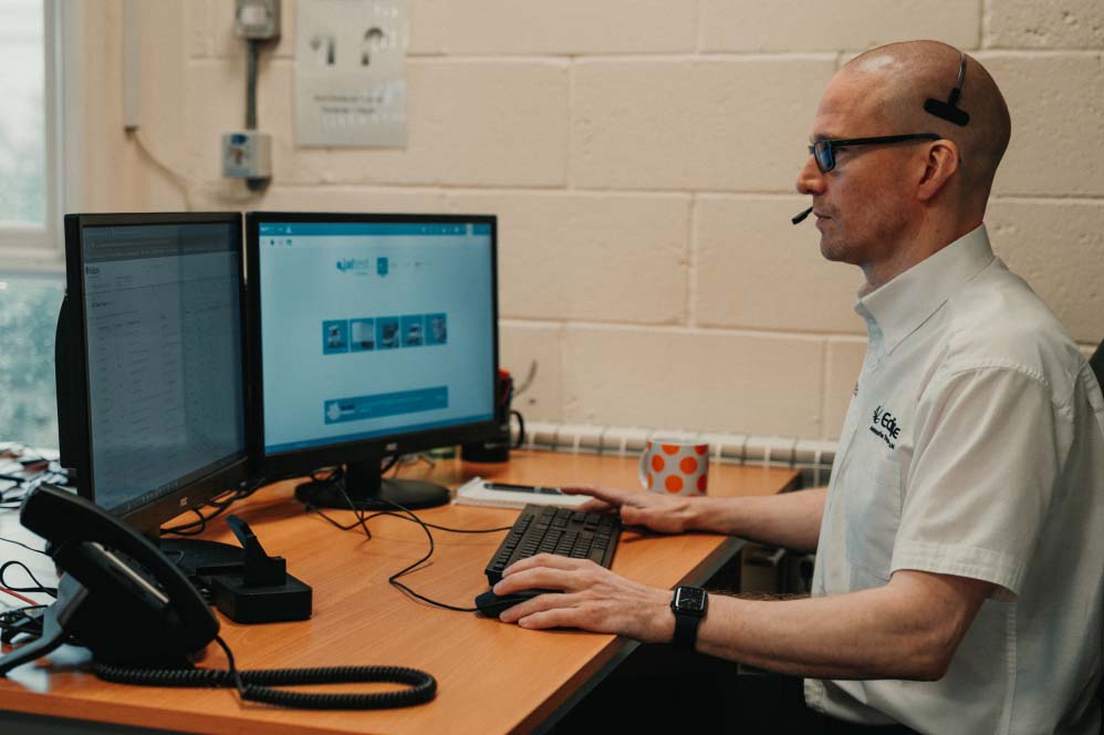 Man at computer desk providing technical support to a customer.